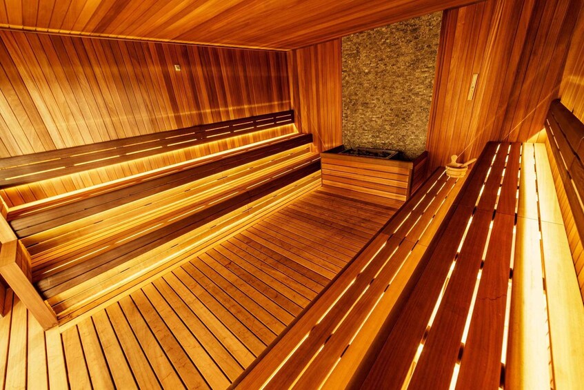 A wooden sauna with benches and a stone wall. 3