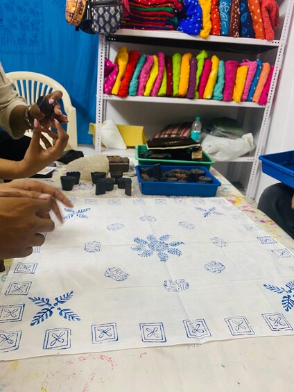 A person arranging small objects on a table with a patterned cloth. 3
