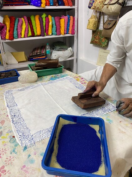 A person working with fabric and a blue powder on a table. 4