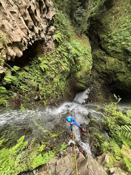 A person rappelling down a rocky cliff with a river flowing below. 1