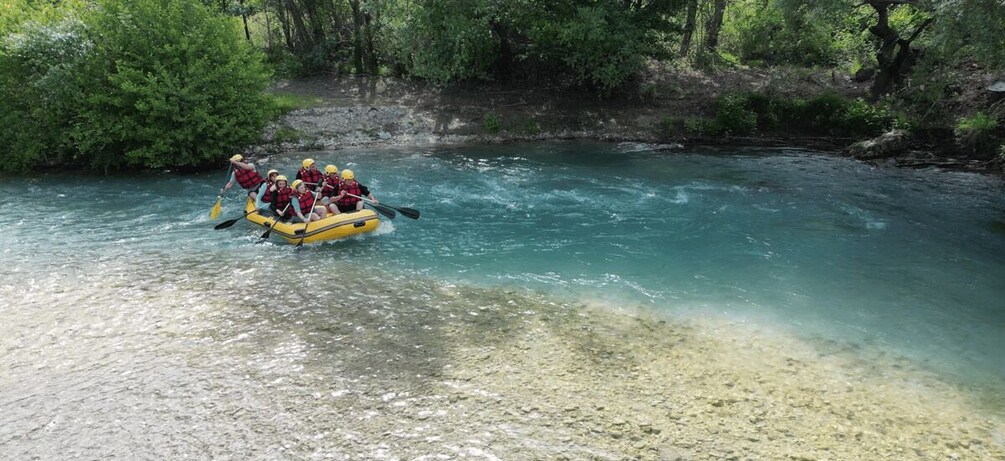 A group of people in a yellow raft navigating a clear river surrounded by dense greenery. 2