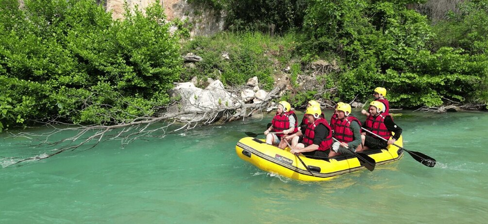 A group of people in a yellow raft on a river surrounded by greenery. 1