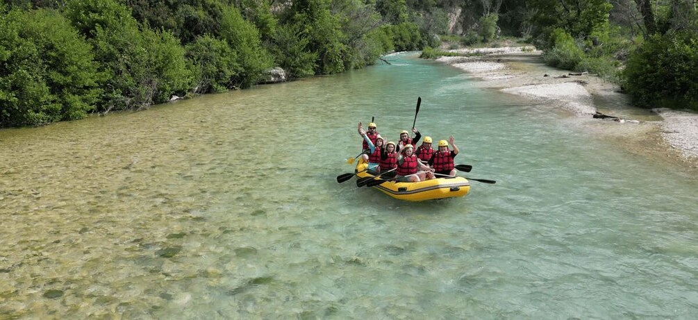 A group of people in a yellow raft on a clear river surrounded by greenery. 5