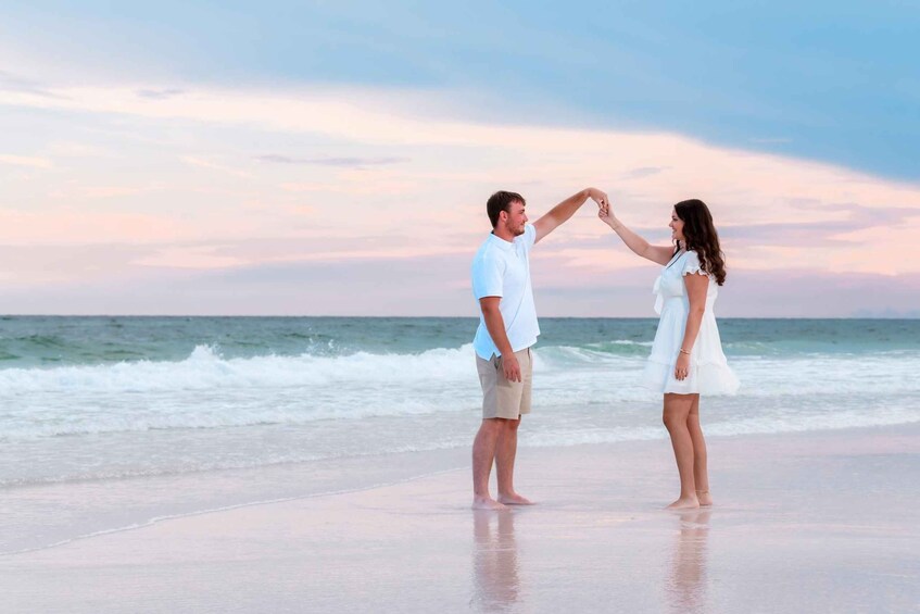 A couple holding hands on a beach with the ocean in the background. 4