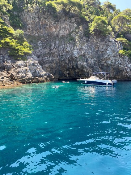 A boat anchored near a rocky cliff with clear turquoise water. 5