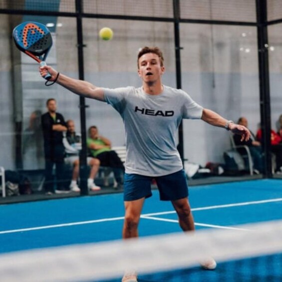 A person playing tennis on an indoor court. 3