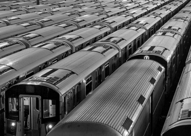 A row of parked trains with reflective metal surfaces and windows. 3