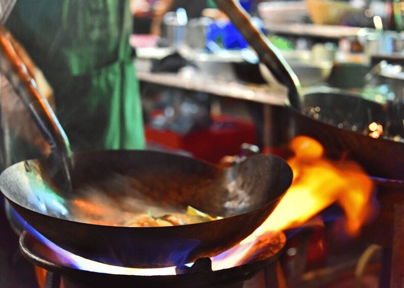 A wok on a stove with food being cooked. 2