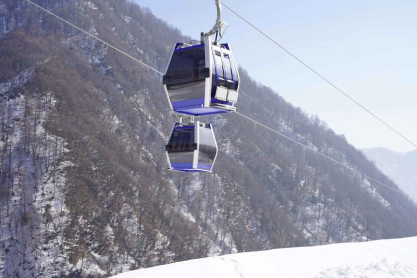 A cable car system with two gondolas suspended by cables against a backdrop of snow-covered mountains. 2