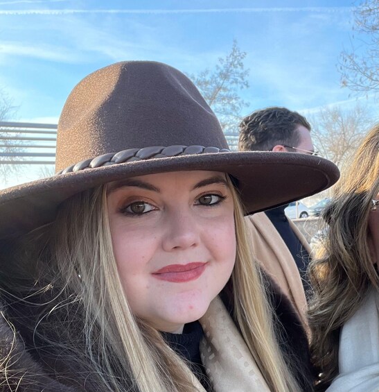 A person wearing a brown hat and a patterned scarf. 3