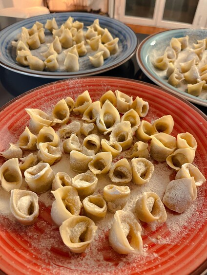 Three plates of ravioli with a dusting of powdered sugar. 5
