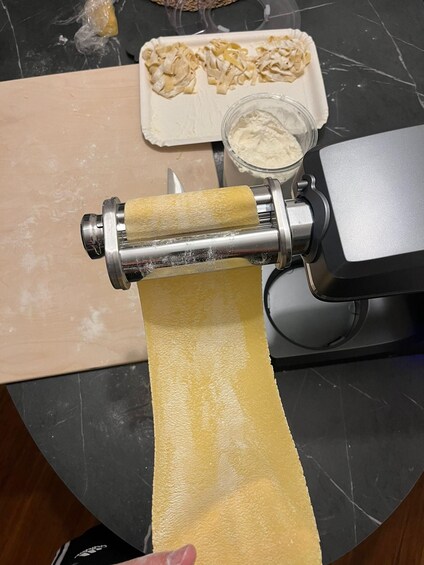 A pasta machine rolling out dough. 1