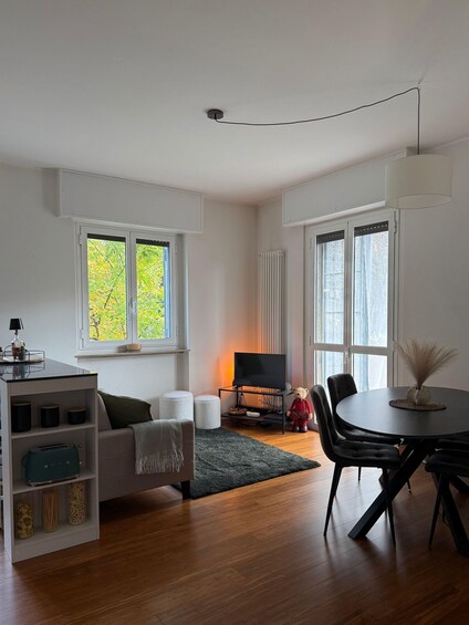 A modern living room with a sofa, a dining table, a TV, and a teddy bear. 2