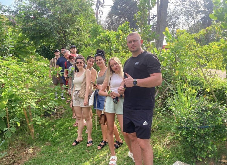 A group of people standing in a garden with various plants and trees. 3
