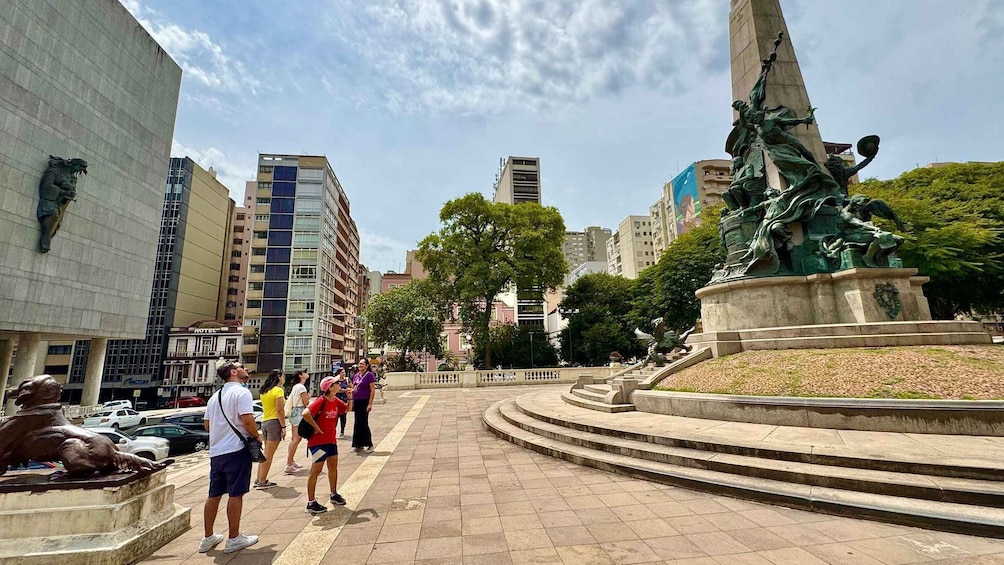 A public square with a statue, steps, and modern buildings. 1