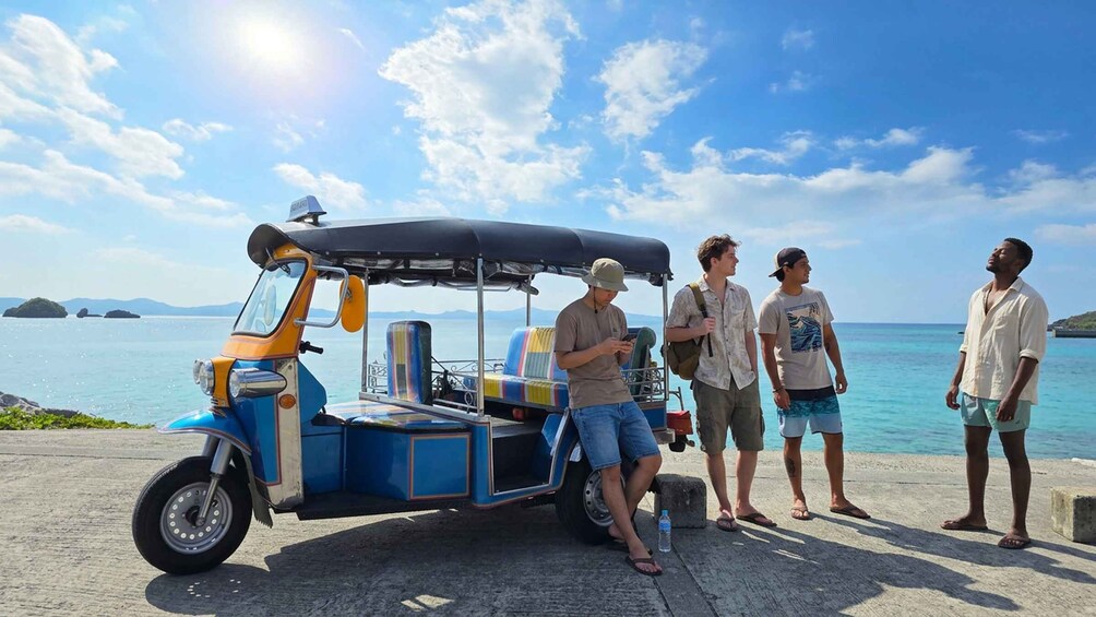 A blue and yellow auto-rickshaw parked by the seaside with a clear sky and calm waters. 3