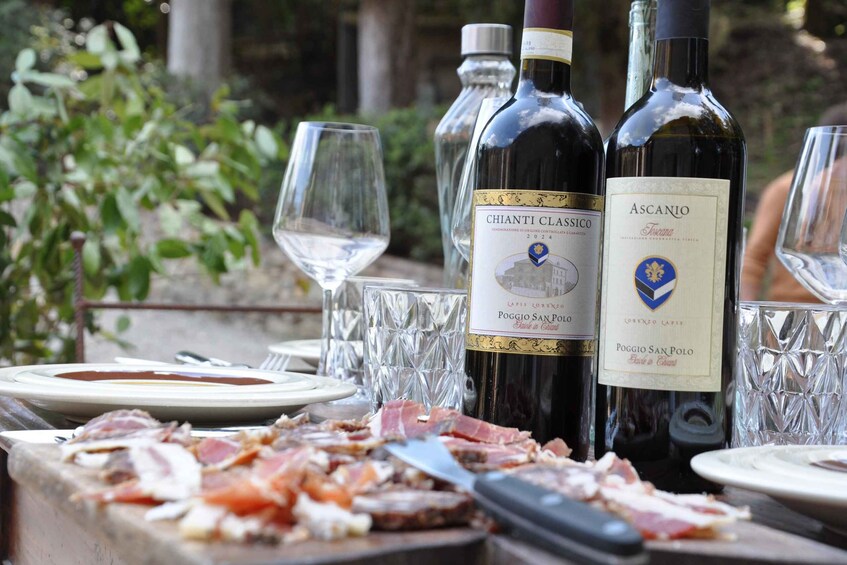 A table with wine bottles, glasses, and a charcuterie board. 4