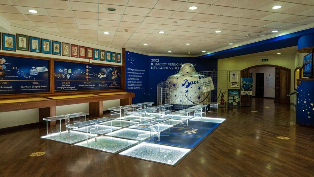 A museum exhibit with a chocolate sculpture, framed pictures on the wall, and a display of chocolate boxes. 4