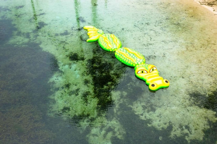 A green inflatable mermaid toy on a beach. 1