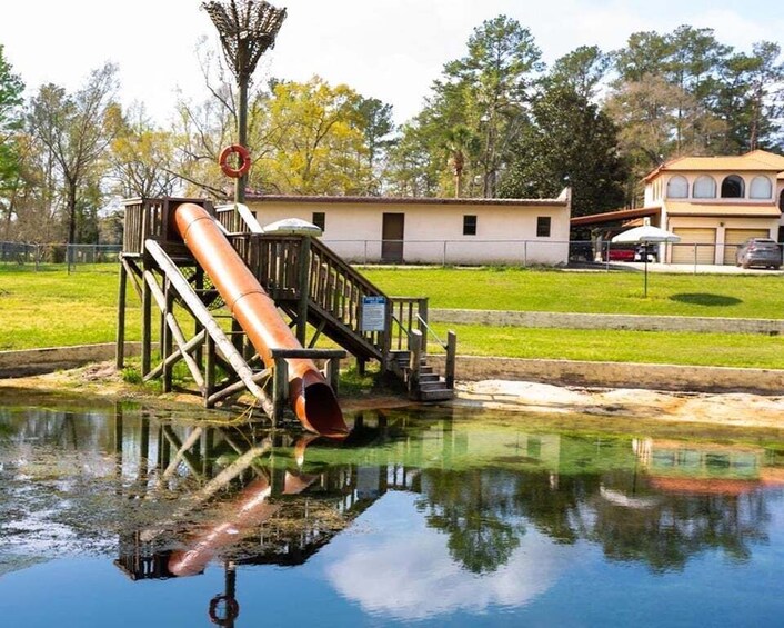 A water slide structure, a house, and a reflection in the water. 5