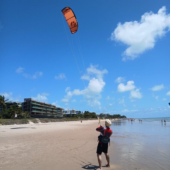 A person kiteboarding on a beach with buildings and palm trees in the background. 5