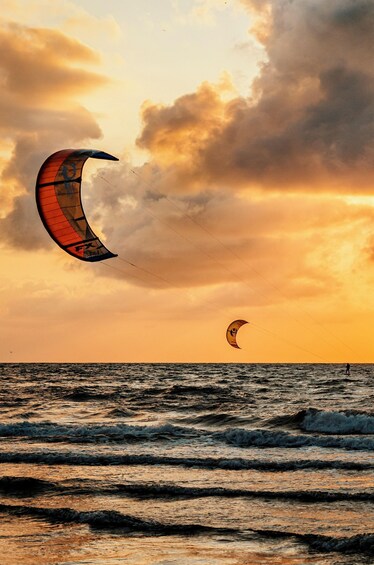 A person kite surfing on the ocean with a sunset in the background. 3