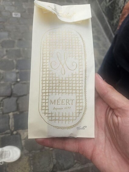 A hand holding a paper with a grid pattern and the word 'MEERT' on it. 4