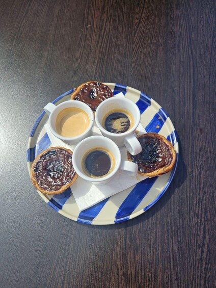 A plate with four pastries and three cups of coffee on a wooden table. 2