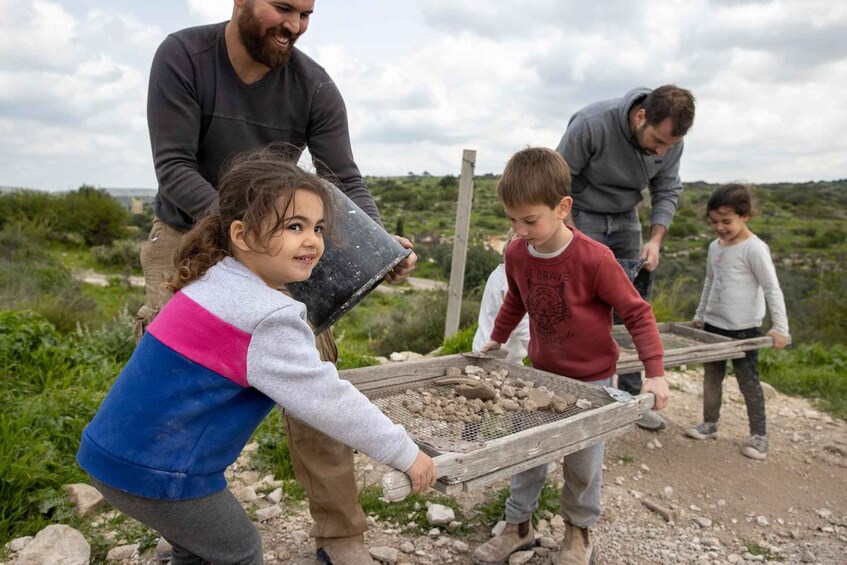 A group of people engaged in outdoor activity, possibly construction or landscaping, with a natural, rocky terrain in the background. 4