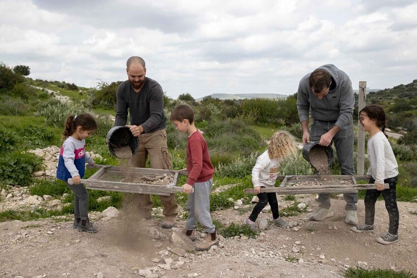 A group of people using wheelbarrows to transport rocks in an outdoor setting. 2