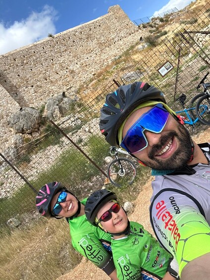 Two people wearing cycling gear with a rocky landscape and a bicycle in the background. 4