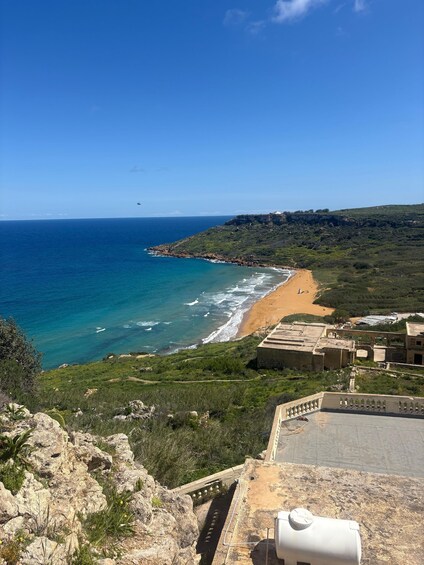 A coastal landscape with a beach, rocky cliffs, and buildings. 2