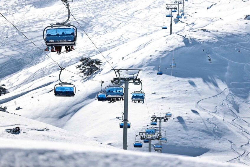 A ski lift with chairs ascending a snowy mountain slope. 4