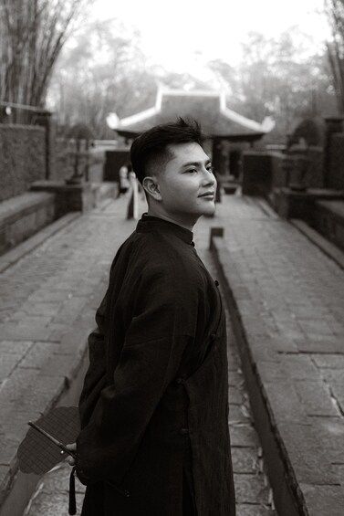 A person in traditional attire standing on a stone pathway with a pagoda in the background. 5