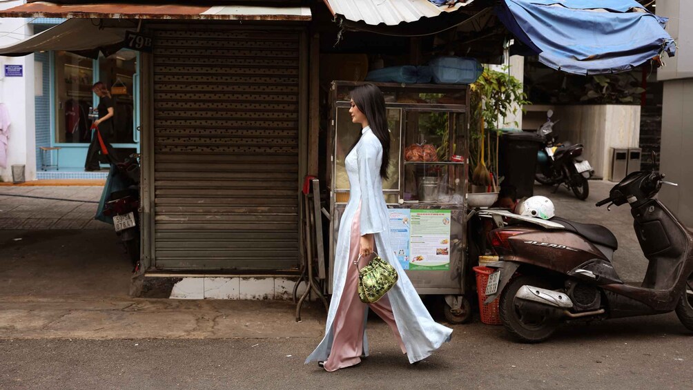 A woman in traditional dress walking past a closed shop with a scooter parked nearby. 4