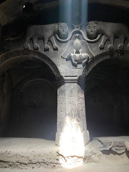 A stone structure with carved animal faces and a central relief. 4