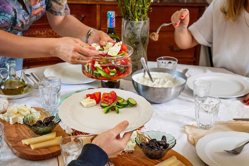 A dining table with a salad, cheese, olives, and a bottle of olive oil. 2