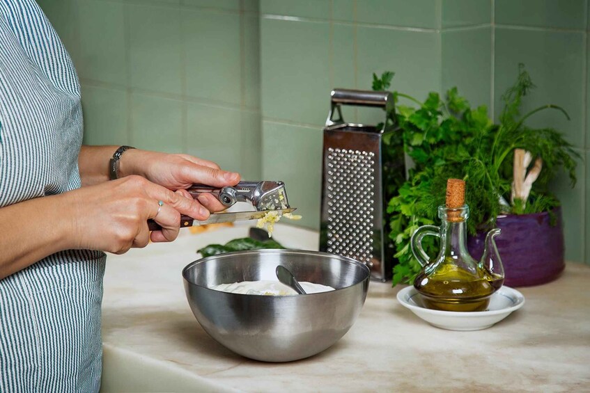 A person grating cheese into a bowl, with a grater and a bottle of olive oil on the counter. 5