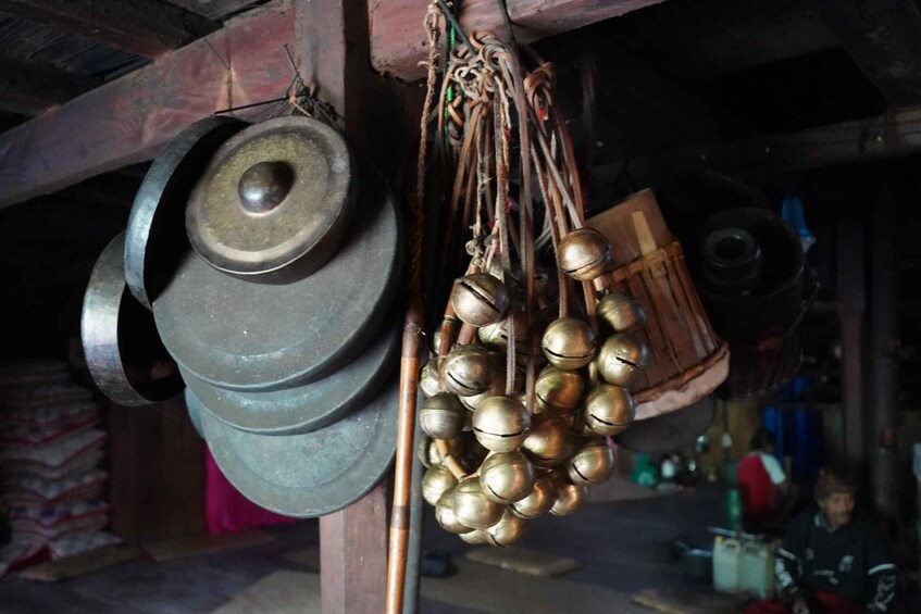 A collection of metal kitchenware, including pots and a set of brass bells, hanging in a rustic setting. 5