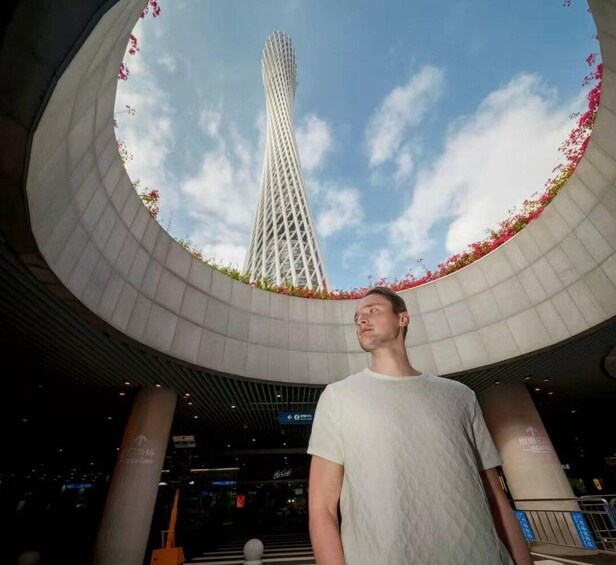 A person standing under a circular structure with a tall tower in the background. 5