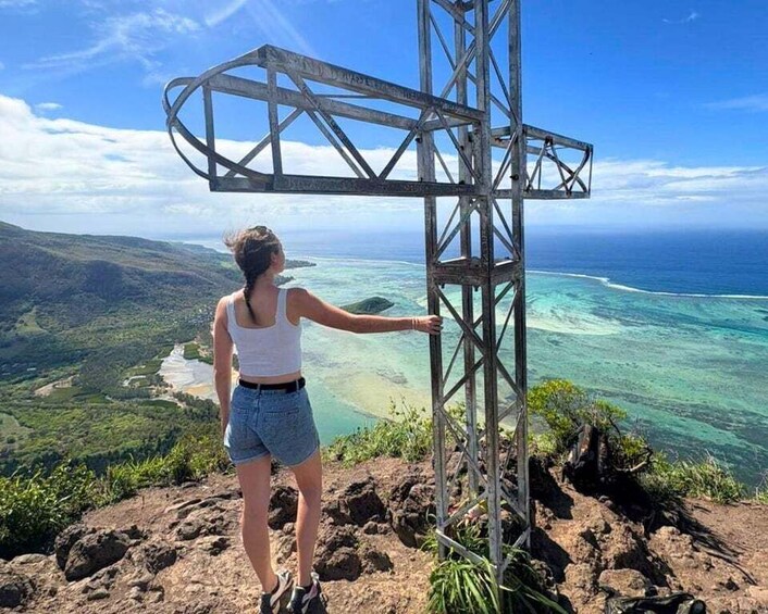 A person standing next to a metal structure with a view of a coastal landscape. 1