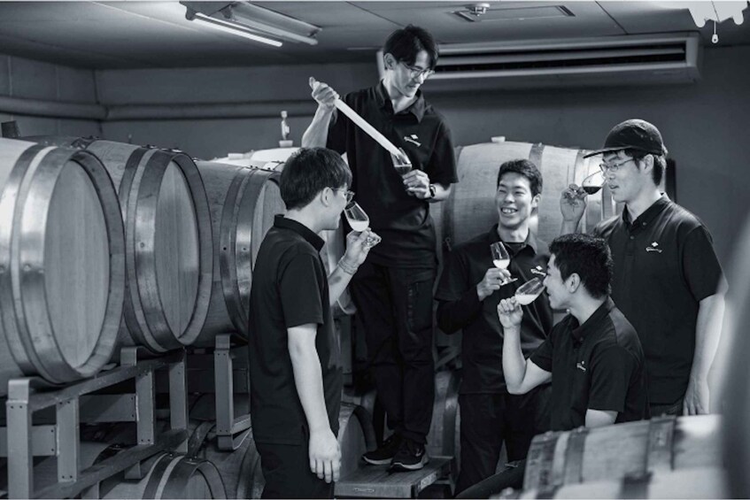 A group of people in a warehouse with large metal barrels. 1