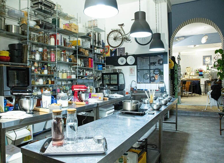 A kitchen with stainless steel appliances, shelves with jars and bottles, and a bicycle hanging on the wall. 4