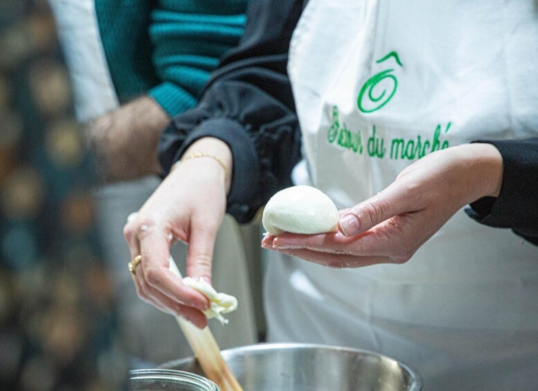 A person holding a white object, possibly dough, with a spoon. 2