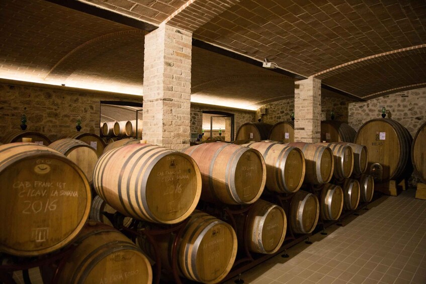 A cellar with wooden wine barrels stacked against stone walls. 2
