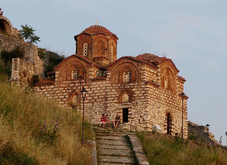 A stone church with a bell tower and a staircase leading up to it. 3
