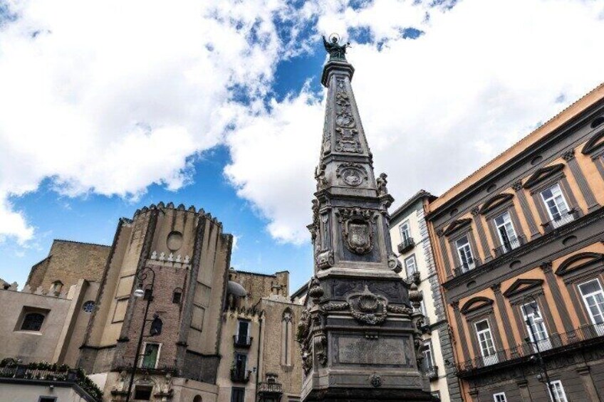 A historic tower with a spire, adjacent buildings, and a clear sky. 4