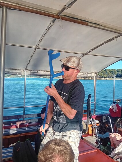 A person on a boat holding a blue paddle, with water and a distant shoreline in the background. 2