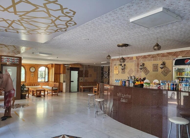 A bar with a counter, stools, and a wall decorated with tiles and a Pepsi refrigerator. 3