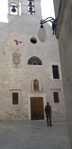 A historic building with a large clock, arched windows, and a statue. 3